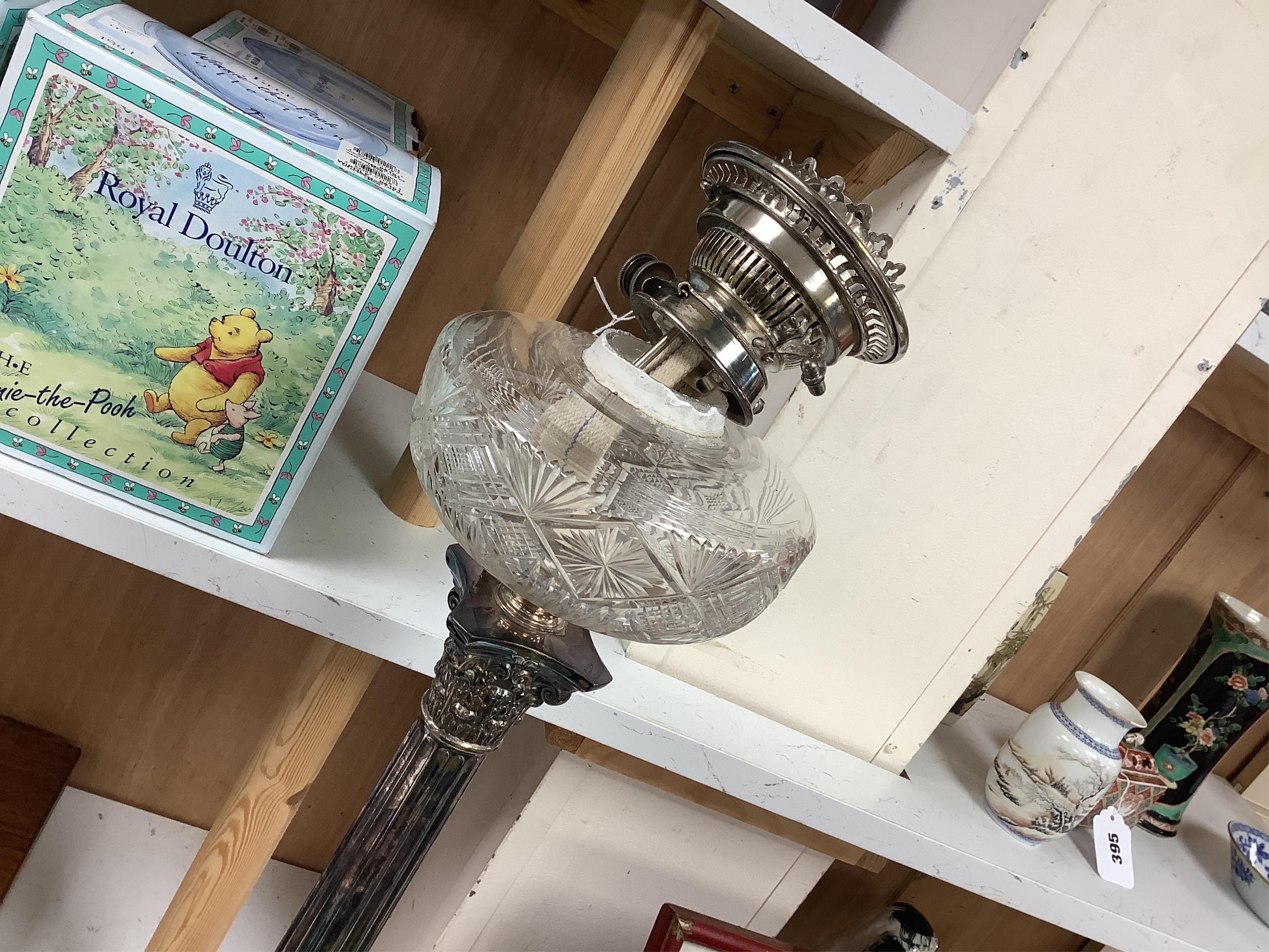 A silver plated oil lamp in the form of a Corinthian column with cut glass reservoir, 76cm high. Condition - fair to good, missing chimney and shade